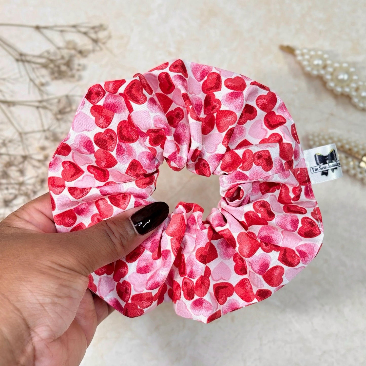 Cotton fabric heart scrunchie held in hand in front of marble background.
