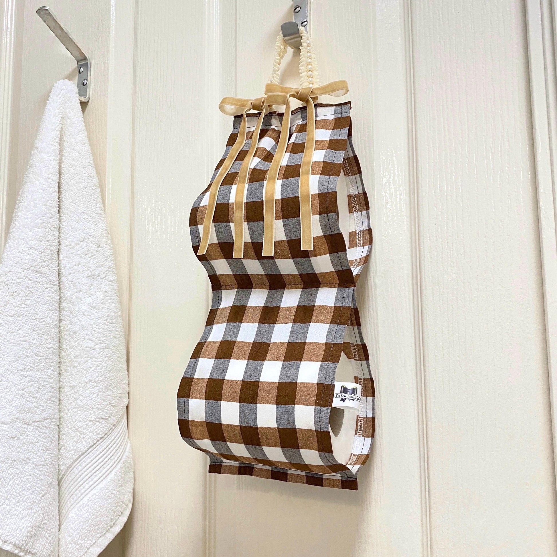 Brown and white gingham fabric toilet roll holder hanging in a bathroom setting.