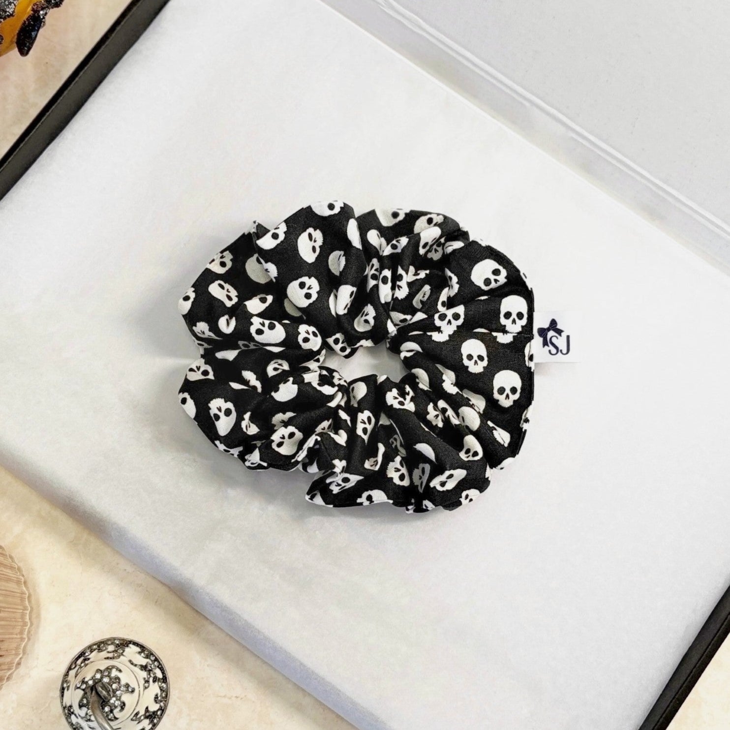 Black Halloween scrunchie with white skull pattern on a white surface