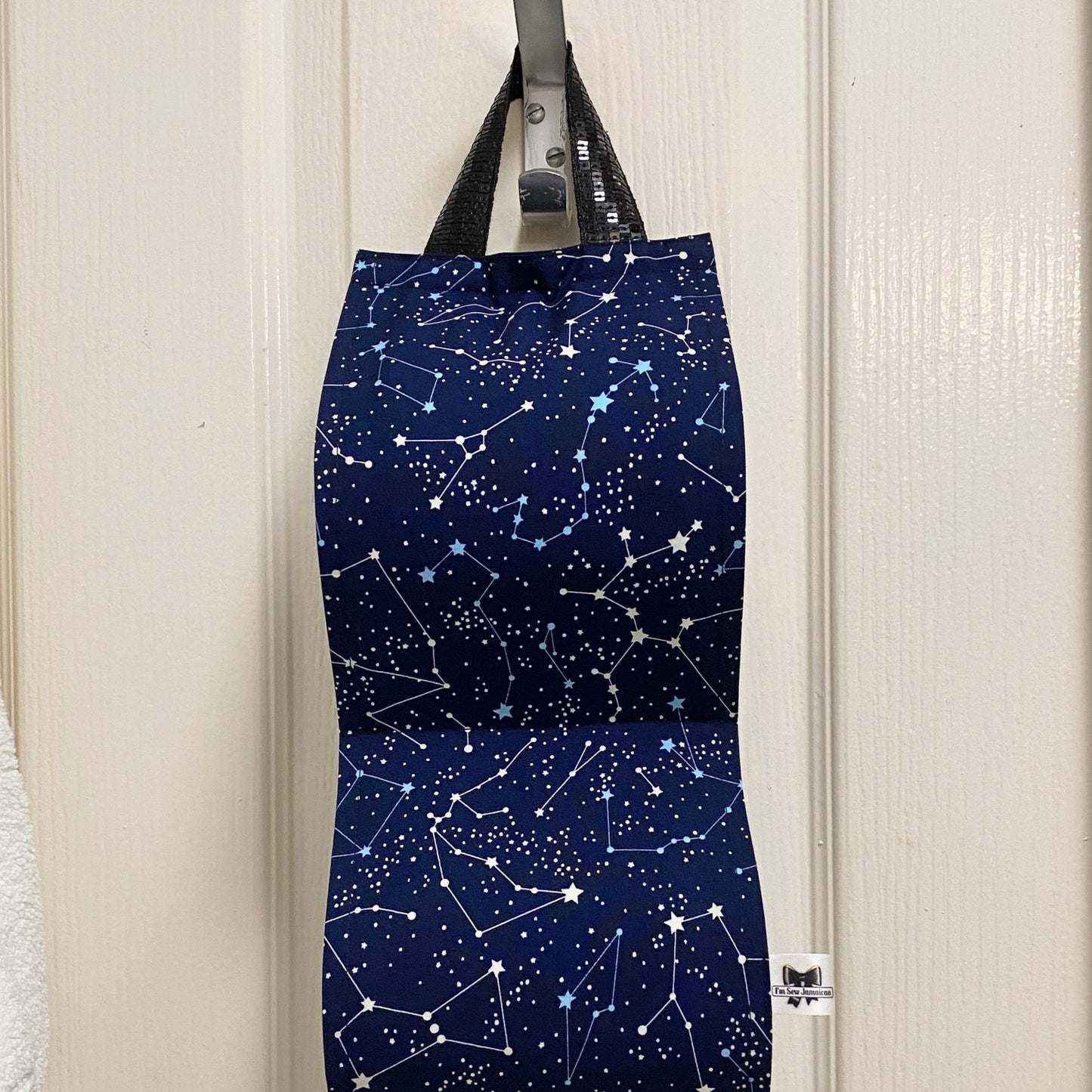 Navy blue night sky fabric toilet roll holder for 2 rolls, hanging in a bathroom setting front view.