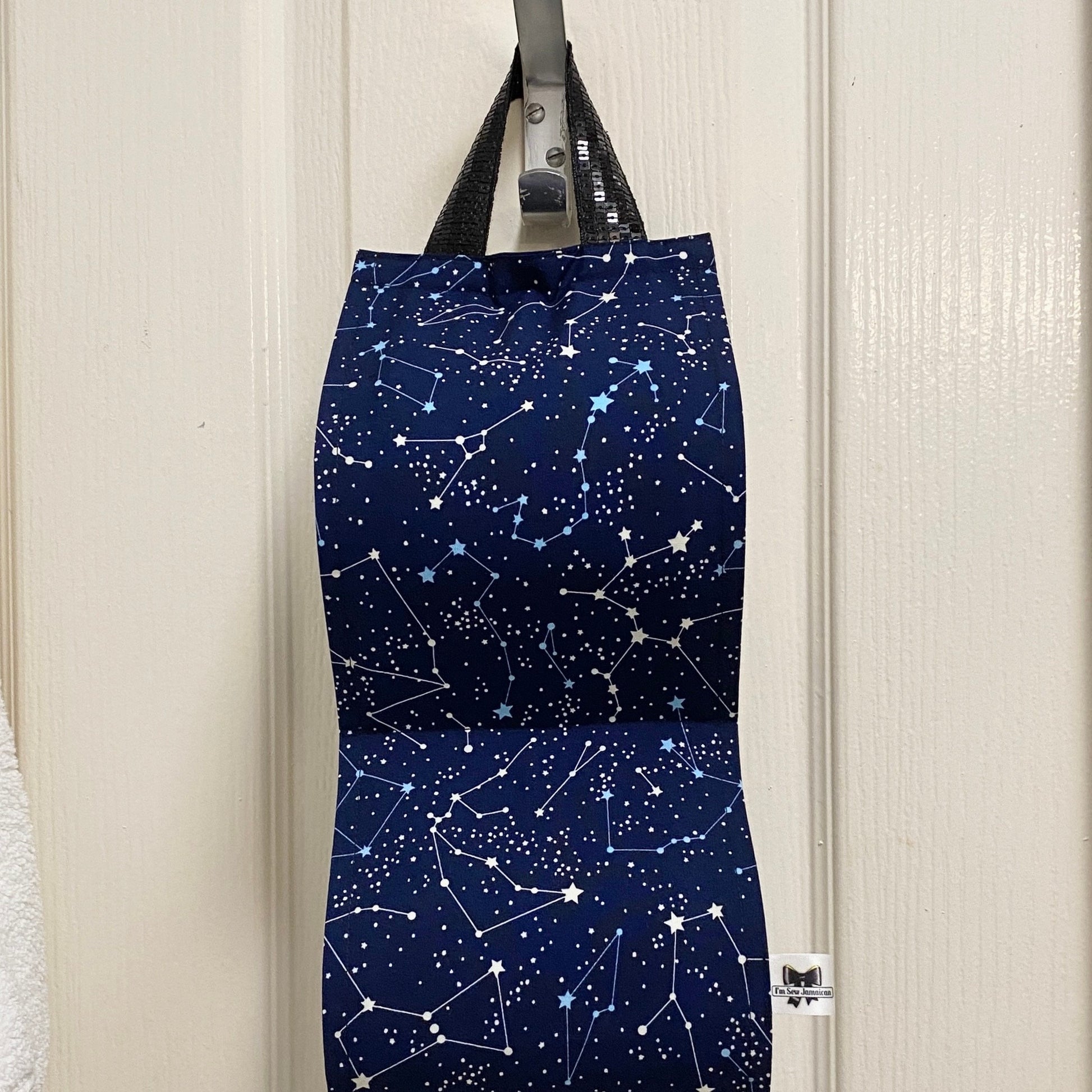 Navy blue night sky fabric toilet roll holder for 2 rolls, hanging in a bathroom setting front view.