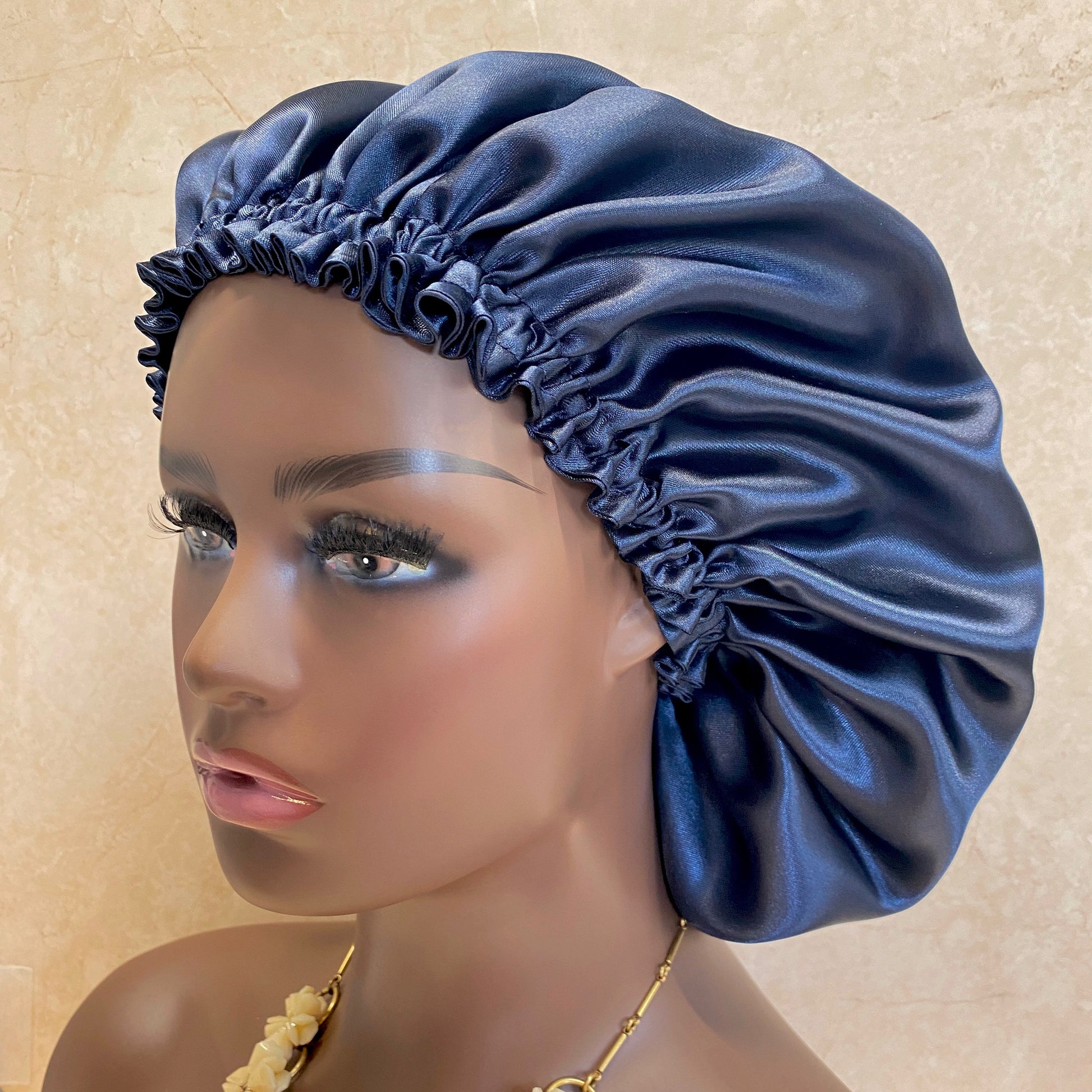 Navy blue satin bonnet displayed on a woman mannequin head, perfect for hair care, night protection. side view.