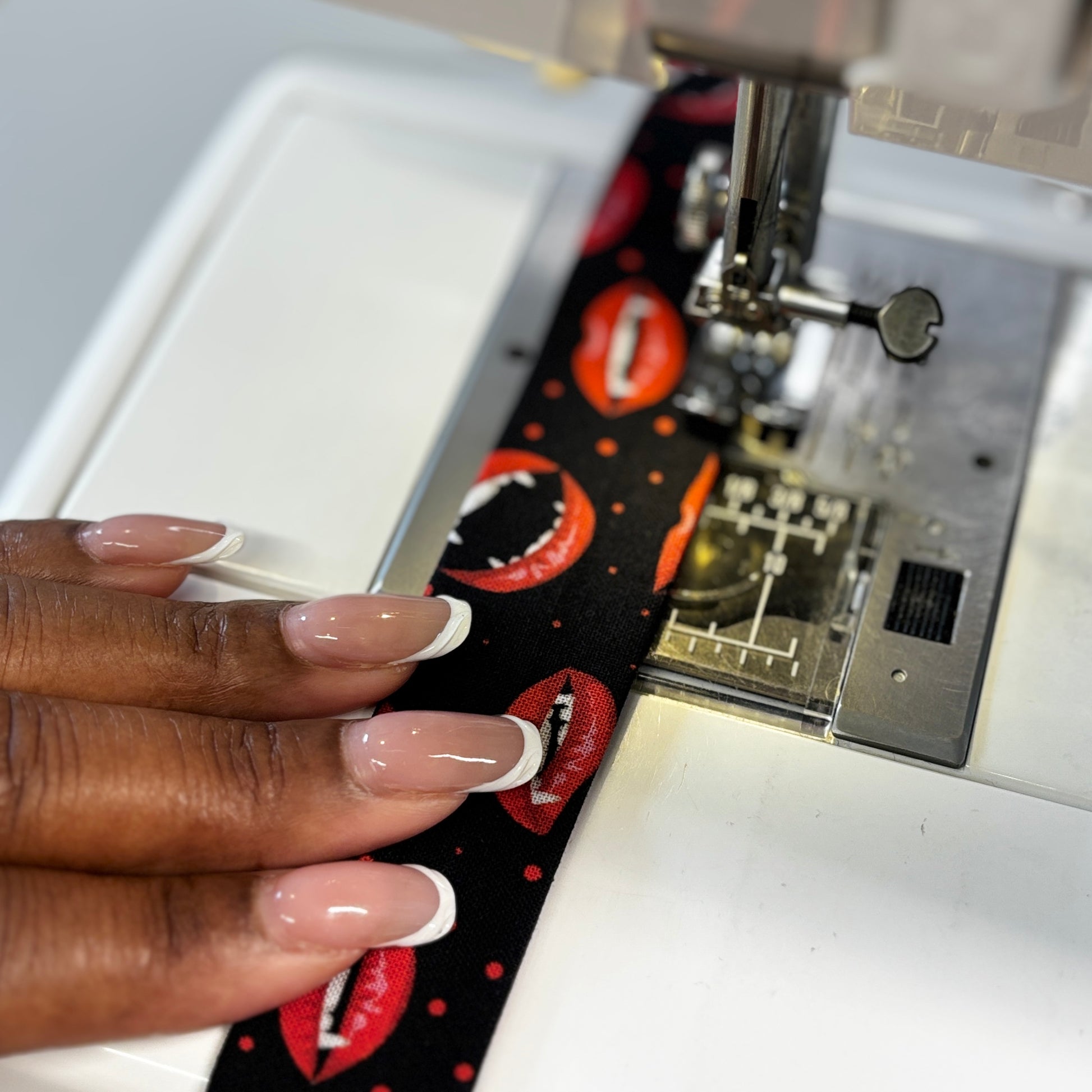 Sewing machine with a person's hand guiding fabric with a lip pattern.