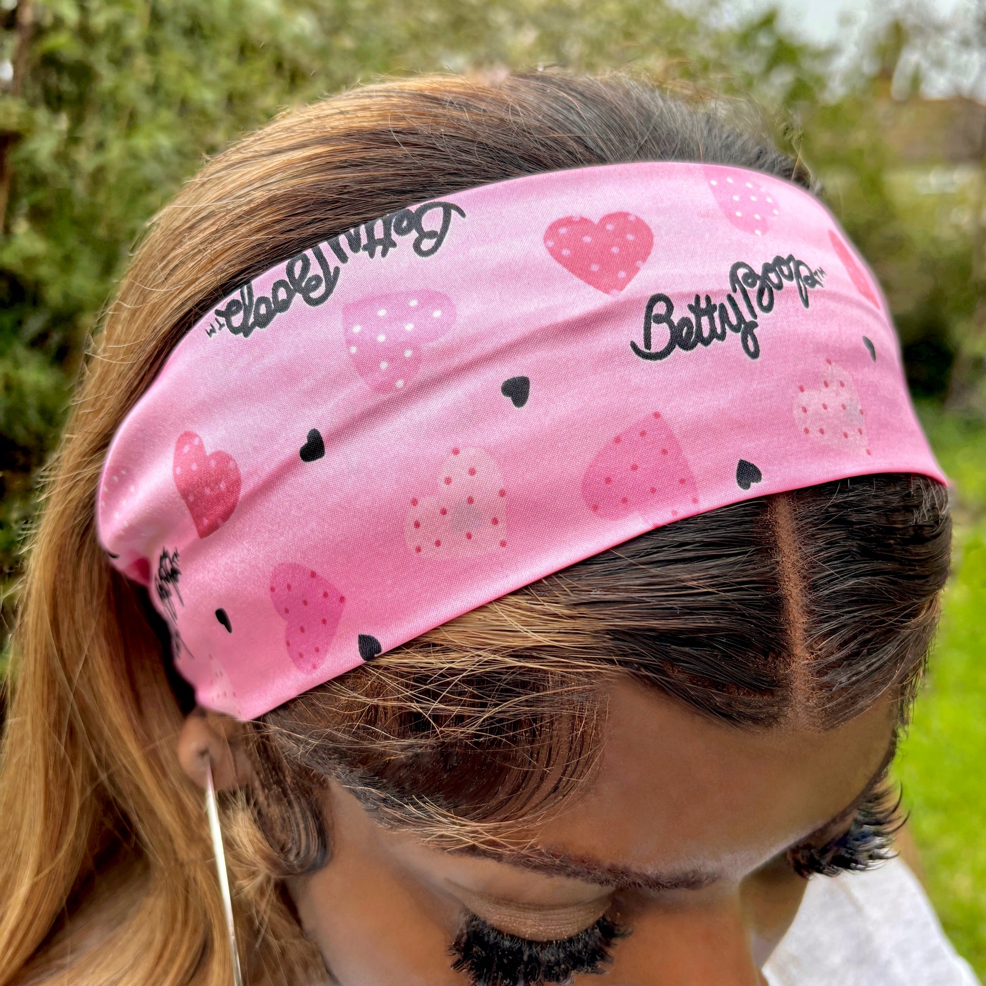 Close-up of pink Betty Boop thick wide flat headband on a Black girl with long blonde hair, head pointing down.