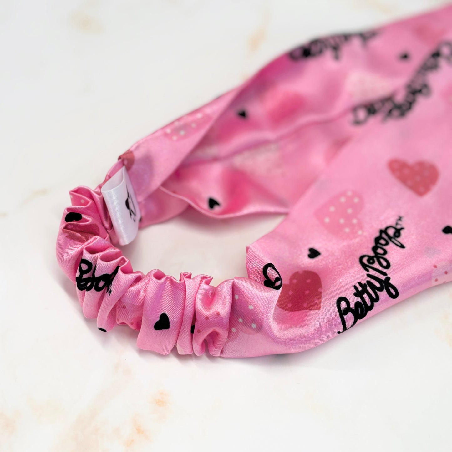 Close up of pink Betty Boop thick wide flat headband in a flat lay with props