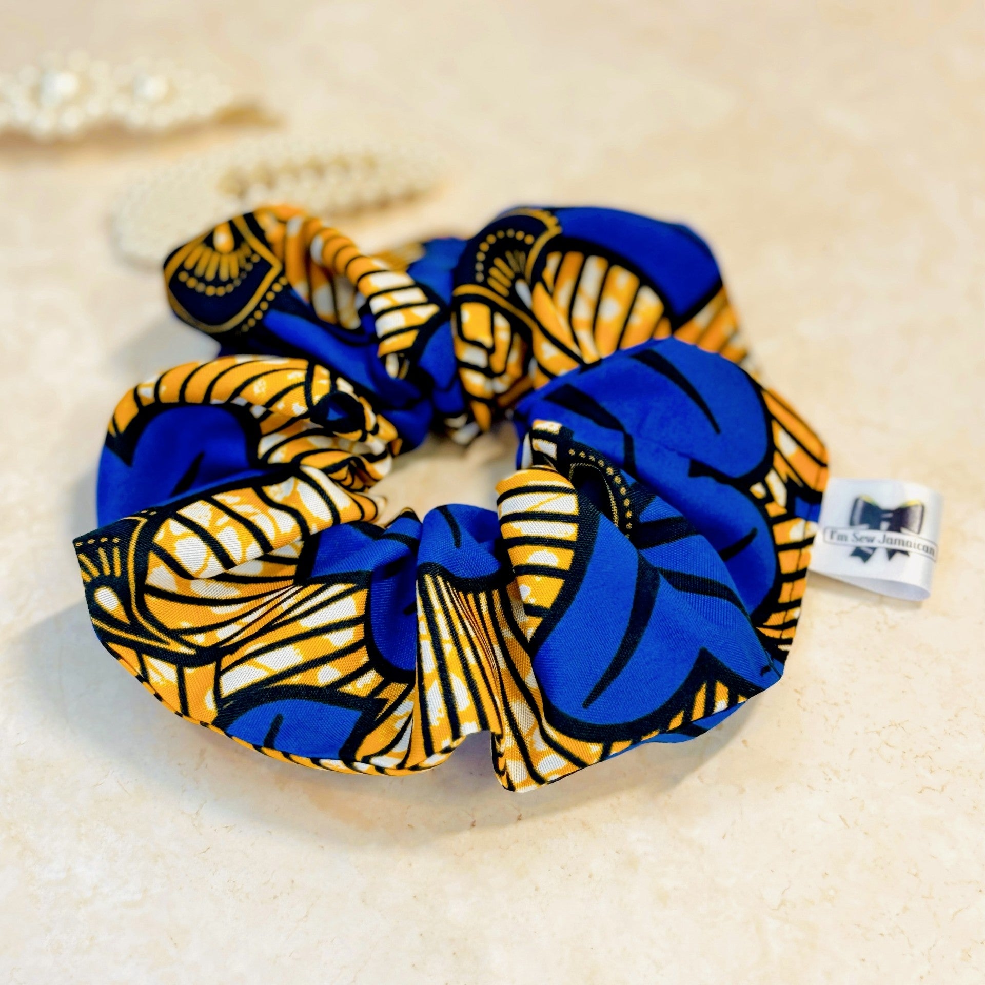 Floral African print blue and yellow scrunchie on marble background.