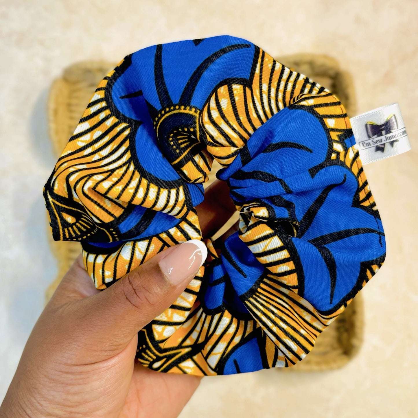 Floral print blue and yellow scrunchie held in hand.