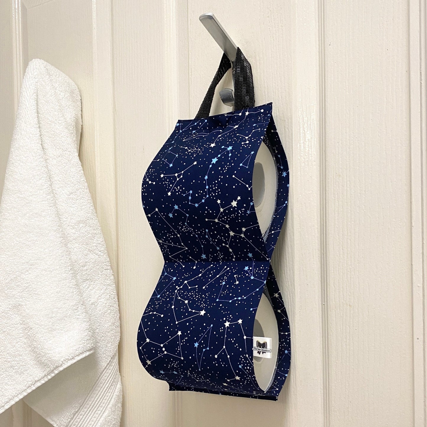 Navy blue night sky fabric toilet roll holder for 2 rolls, hanging in a bathroom setting.