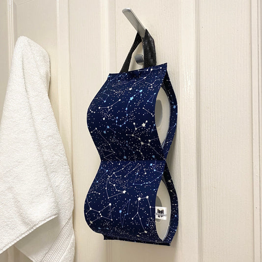 Navy blue night sky fabric toilet roll holder for 2 rolls, hanging in a bathroom setting.