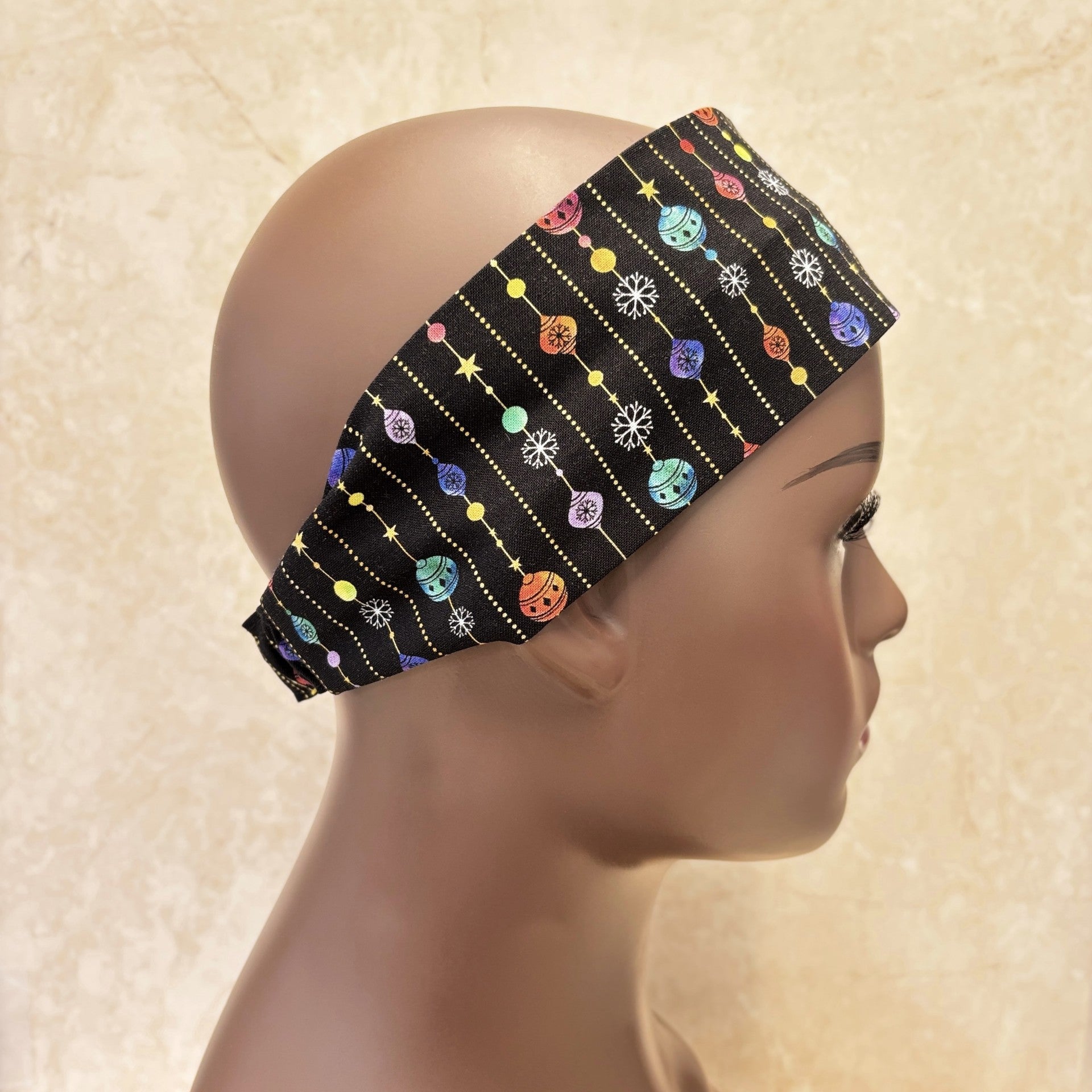Black Christmas headband with colourful patterns on a mannequin head against a beige background
