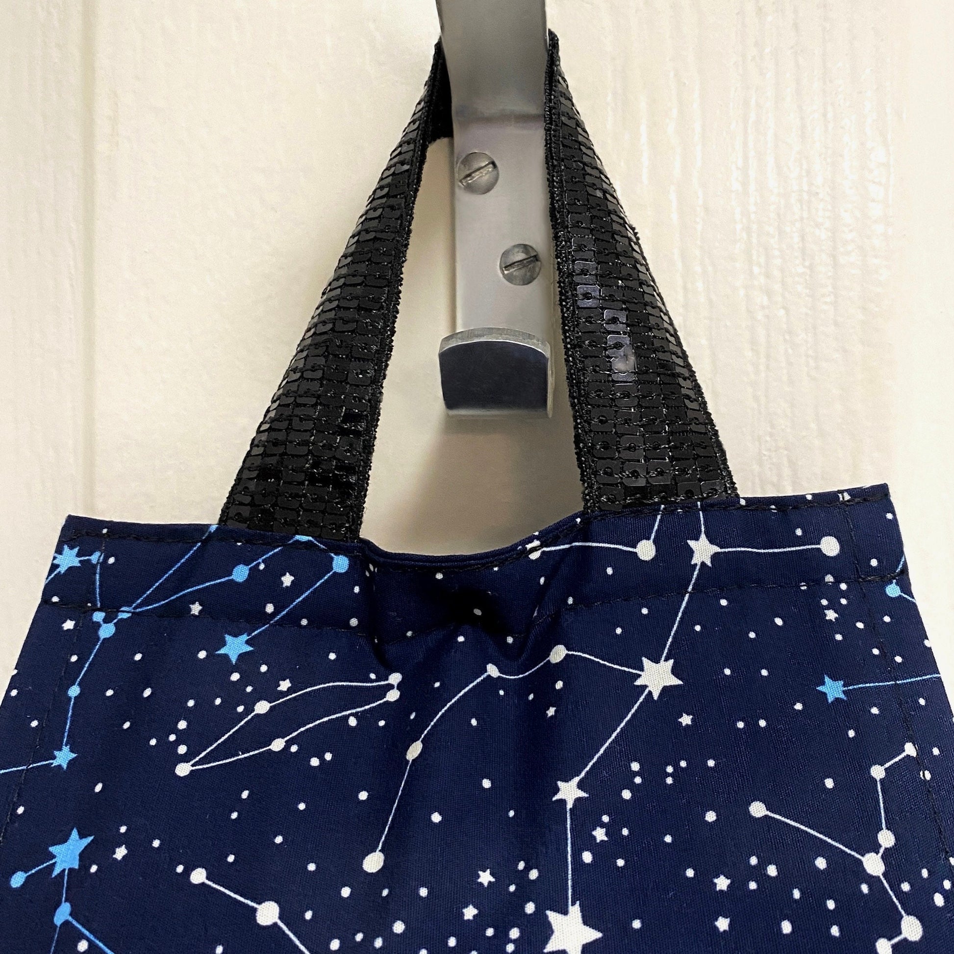 Close up navy blue night sky fabric toilet roll holder hanging in a bathroom.