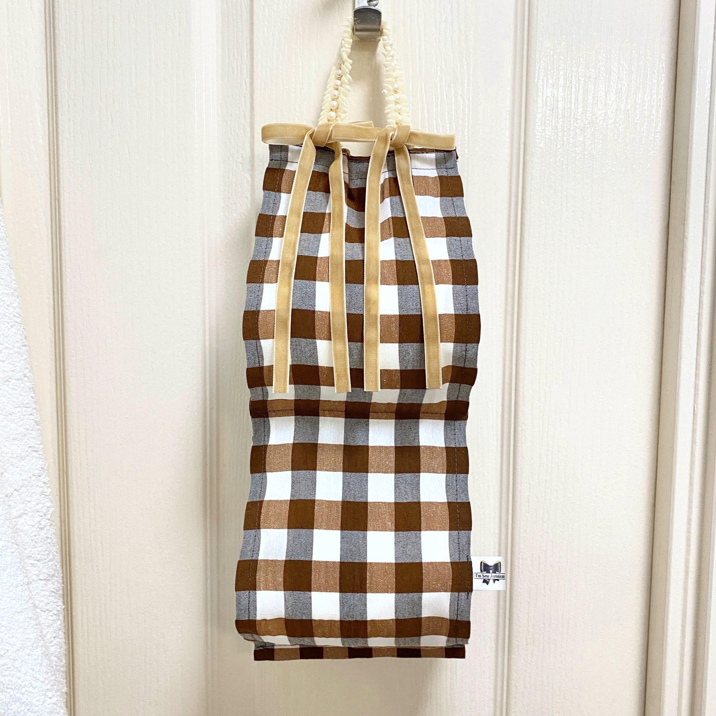 Brown and white gingham fabric toilet roll holder front view hanging in a bathroom setting.