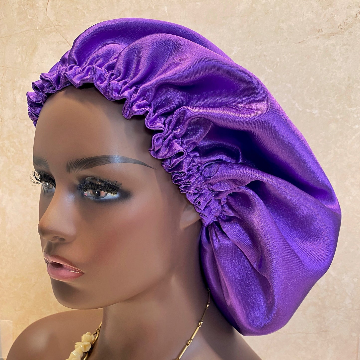 purple satin bonnet displayed on a woman mannequin head , side profile view.
