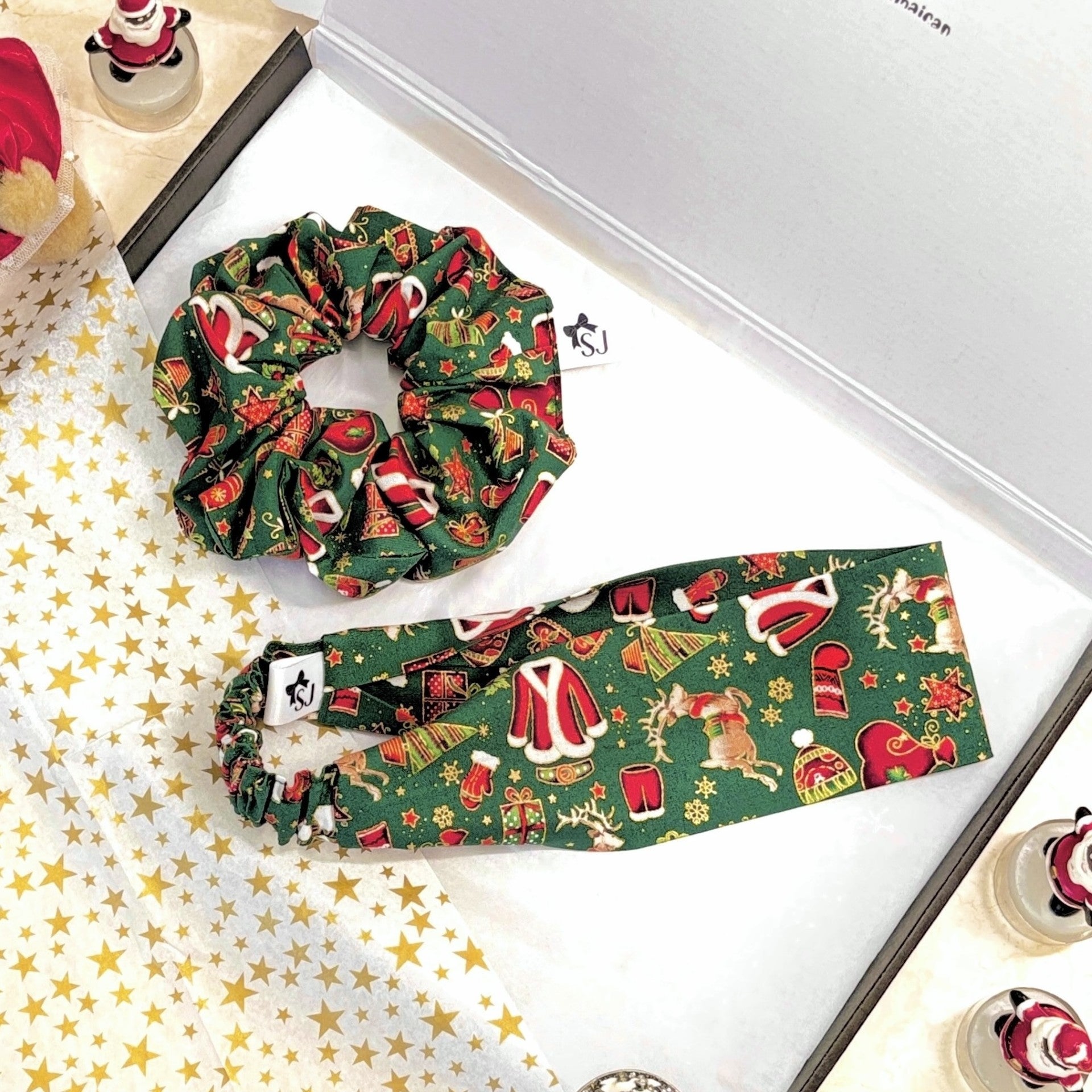 Green Christmas scrunchie and headband on a decorative gift box with gold stars tissue paper.