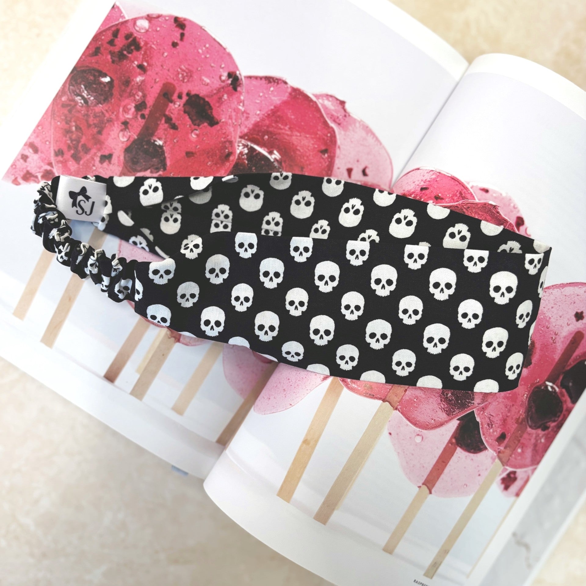 Black Halloween headband with white skull pattern on a magazine page 
