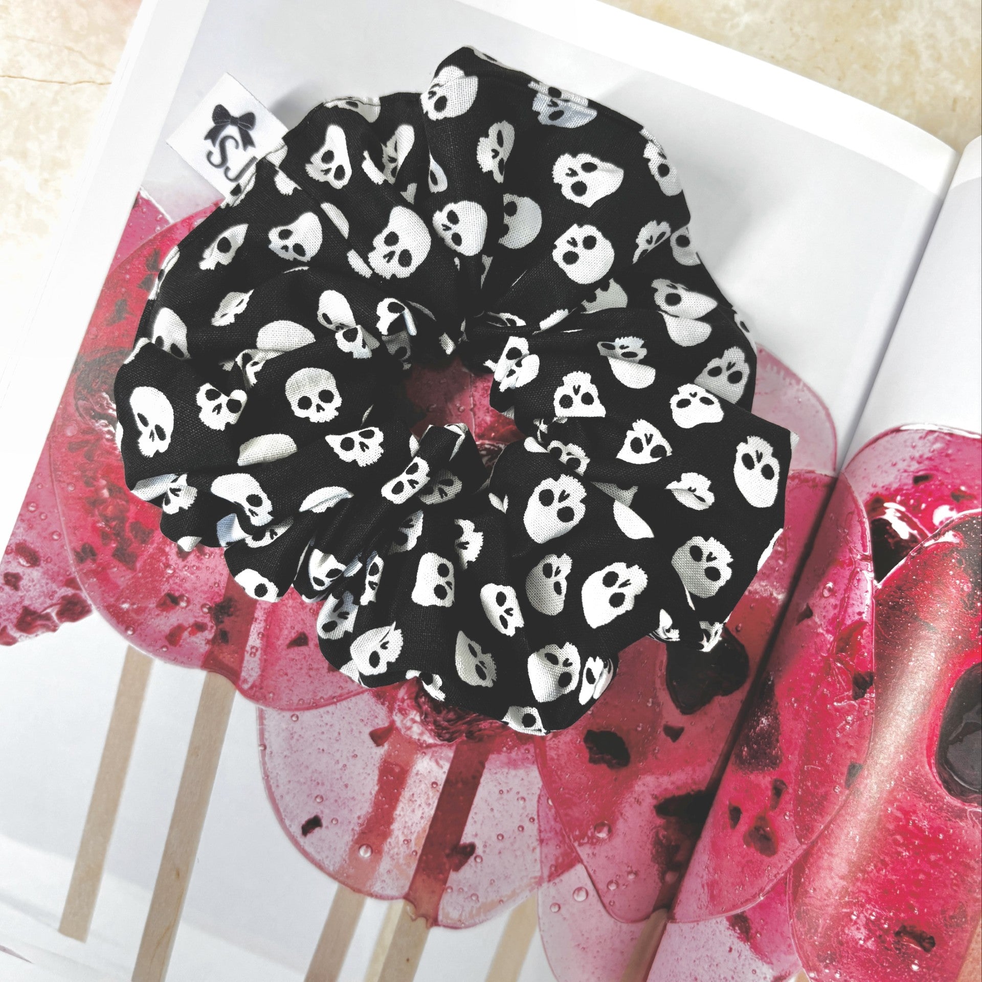 Black Halloween scrunchie with white skull pattern on a pink flower background