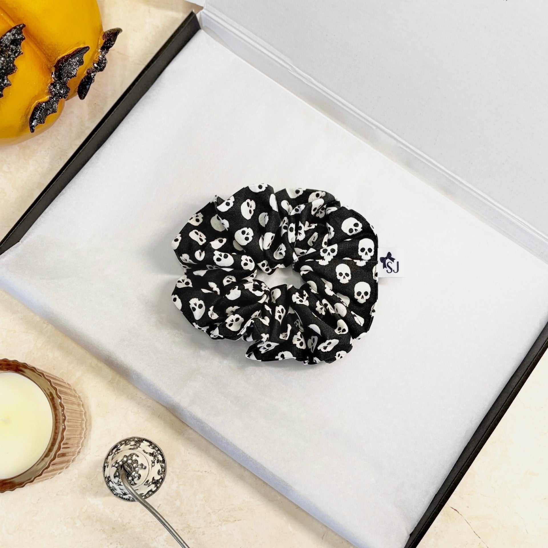 Black Halloween scrunchie with white skull pattern on a white surface