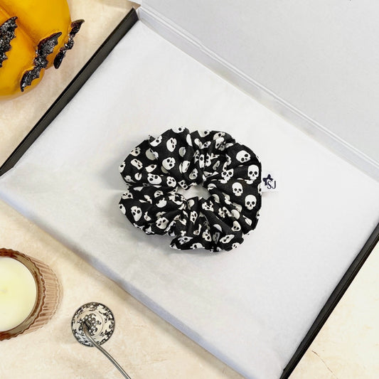 Black Halloween scrunchie with white skull pattern on a white surface
