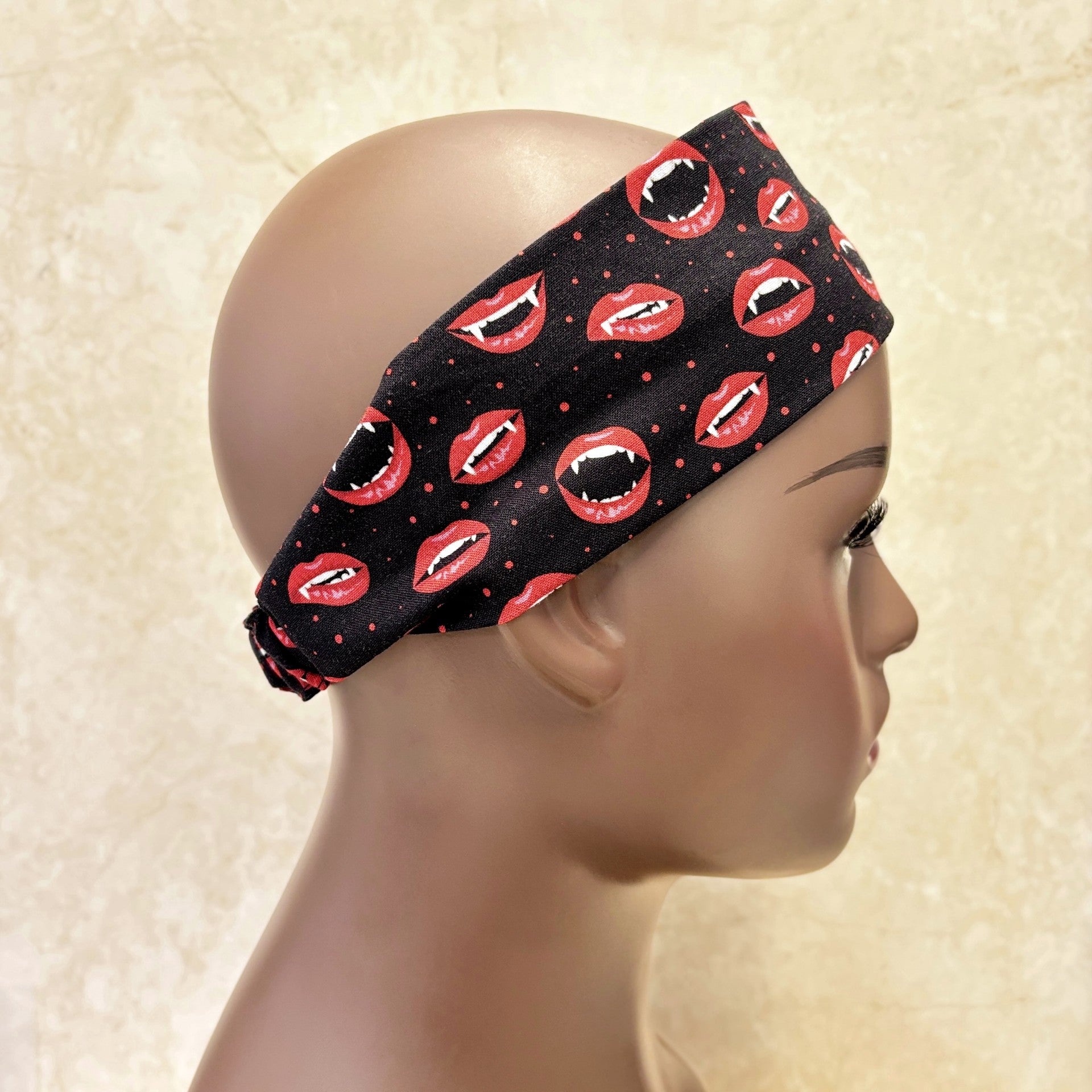 Black headband with red lip prints on a mannequin head against a beige background