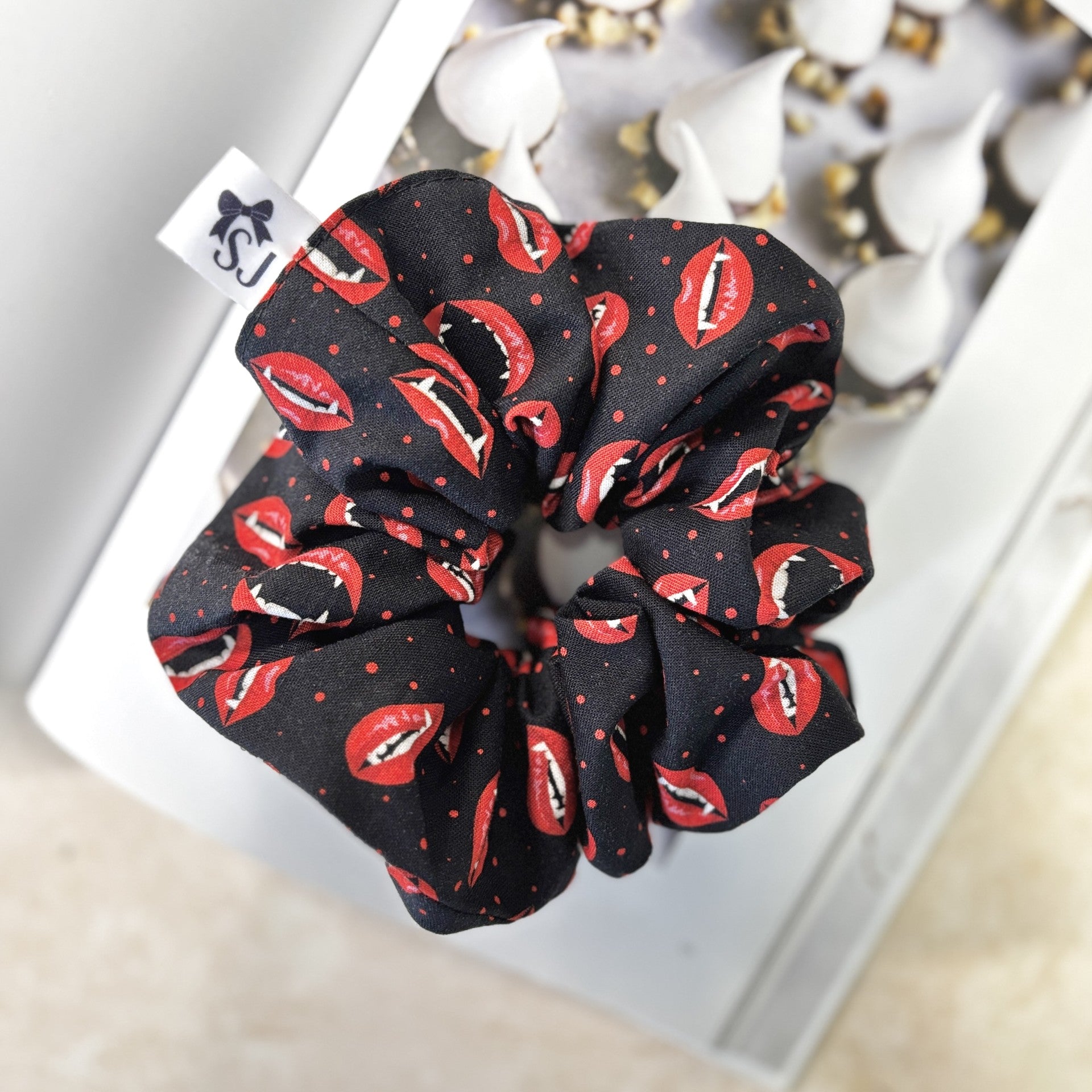 Black Halloween scrunchie with red lip print on a book