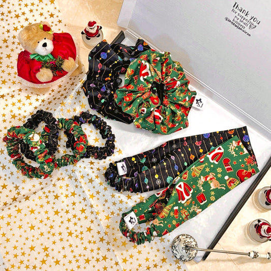 Collection of Christmas-themed hair scrunchies and headbands in a gift box with a teddy bear and small figurines.