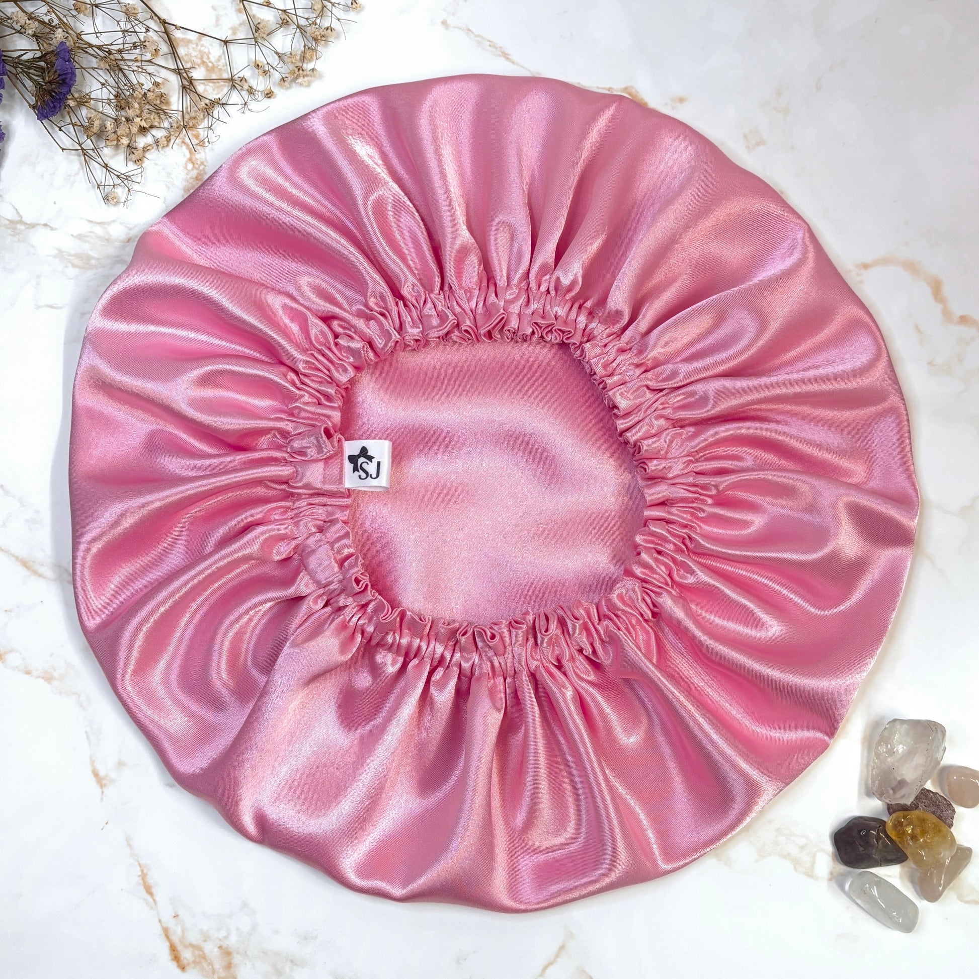 pink satin bonnet stacked on plain background