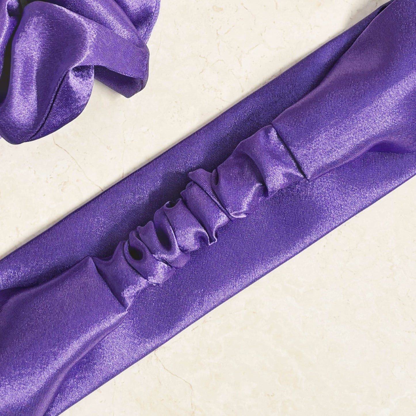 Purple satin headband with a thick, wide top and elastic back
